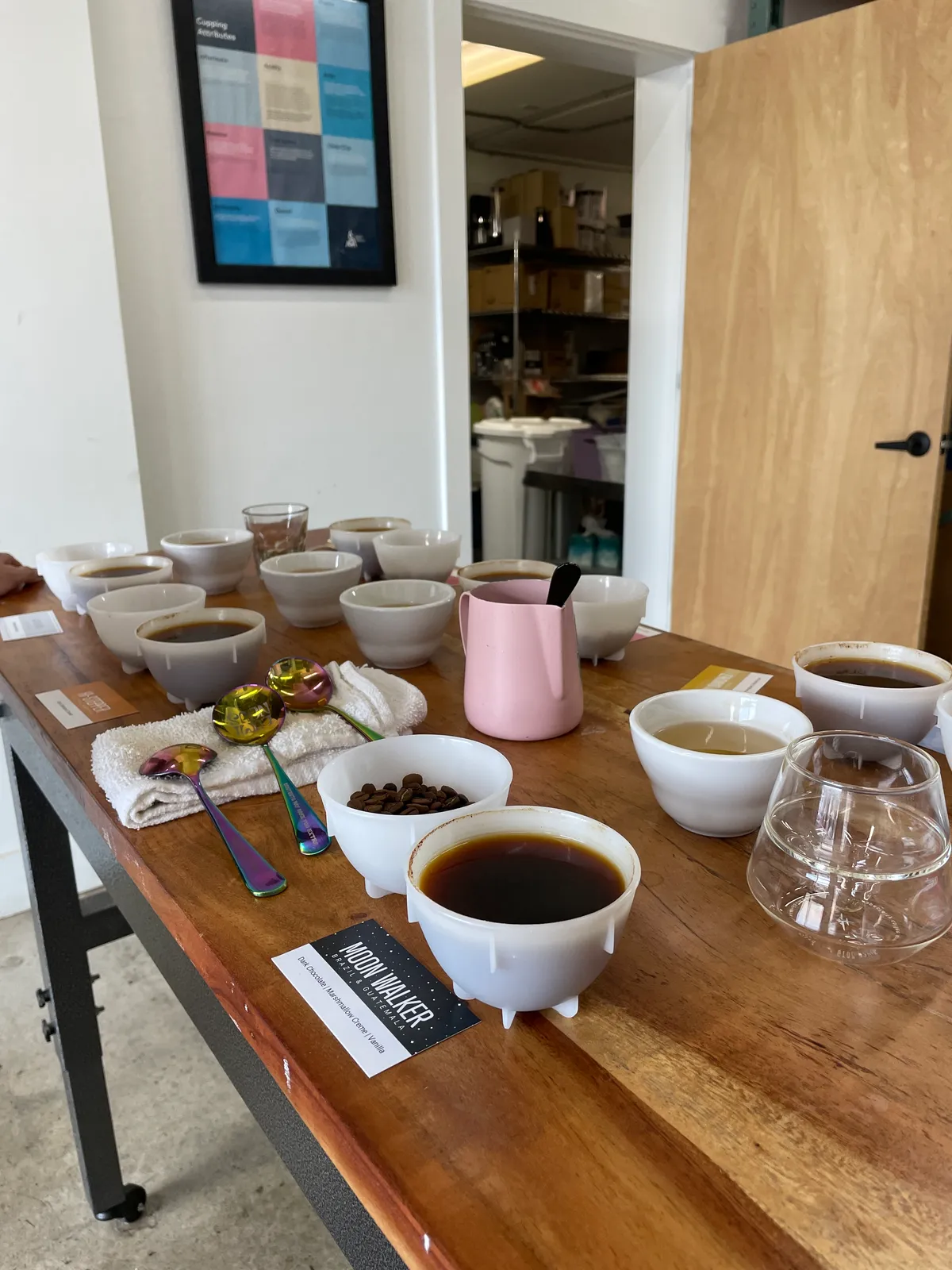 Cupping table at the Brass Horn roaster covered in tasting bowls, sample cards, and spoons